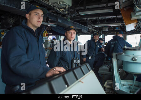 AUGUSTA BAY, Italien (11. Dezember 2014) – Ensign Samuel Hadik, zentrieren, aus Chester, New Hampshire, Monitore zivilen Handelsschiffe Gegenverkehr, wie USS Cole (DDG-67) Augusta Bay fährt nach einem geplanten Hafen-Besuch 11. Dezember 2014. Cole, ein Zerstörer der Arleigh-Burke-Klasse-geführte Flugkörper in Norfolk, Gridley führt Marinebetriebe in den USA 6. Flotte Bereich der Maßnahmen zur Erhöhung der Sicherheit der Vereinigten Staaten in Europa interessiert. Stockfoto