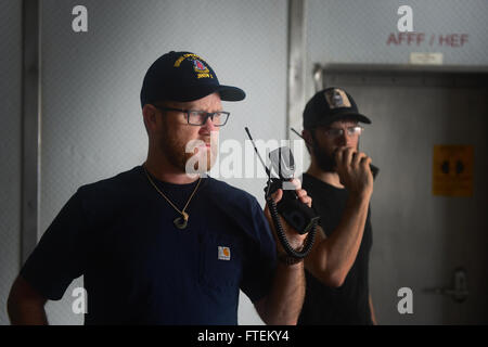 Atlantik (13. Februar 2015) Second Officer Ray Barnett, links, hört Funkverkehr wie Zivildienst Seeleute einen simulierten Brand-Wirkungs-Bohrer auf das Military Sealift Command gemeinsame High-Speed-Schiff USNS Speerspitze (JHSV 1) 13. Februar 2015 durchzuführen. Speerspitze ist auf eine geplante Bereitstellung in die USA 6. Flotte Einsatzgebiet zur Unterstützung der internationalen Zusammenarbeit Kapazitäten Programm Afrika Partnerschaft Station. (Foto: U.S. Navy Mass Communication Specialist 1. Klasse Joshua Davies/freigegeben) Stockfoto