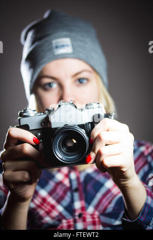 Porträt von Hipster Mädchen unter Bild mit Retro-Kamera in karierten Hemd und Wintermütze. Stockfoto