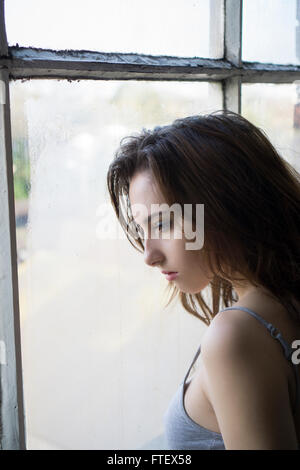 Profil von einer schönen jungen Frau aus dem Fenster Stockfoto