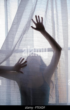 Geheimnisvolle Frauengestalt hinter die Vorhänge am Fenster Stockfoto
