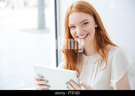 Gerne schöne junge Frau lachend und mit Tablet im café Stockfoto