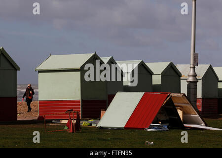 Brighton, UK. 28. März 2016. Ein Passant sieht beschädigte Strandhütten in Hove nach Wind und Regen durch Sturm Katie brachte die Küste in Brighton, East Sussex, UK Montag, 28. März 2016 zerschlagen. BBC berichten "Sturm Katie Böen von bis zu 105 km/h Misshandlung von England und Wales, mit mehreren Flügen von Flughäfen umgeleitet gesehen hat und große Brücken geschlossen". Bildnachweis: Luke MacGregor/Alamy Live-Nachrichten Stockfoto