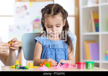 Niedliche kleine Mädchen Formen aus Plastilin auf Tisch Stockfoto