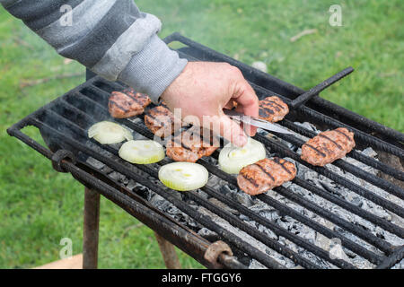 Grill im Freien. Männer hand gebratene Frikadellen auf dem Grill. Stockfoto