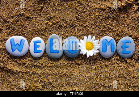 Willkommen Wort buchstabieren aus Steinen mit Briefen und Blume auf Meeressand. Briefe von mir gezeichnet Stockfoto