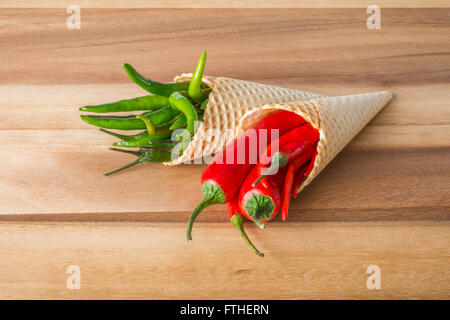 Rot und grün hot Chili Peppers in Wafer Kegel auf hölzernen Hintergrund Stockfoto