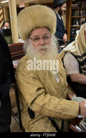 Porträt eines Rabbiners in einer Synagoge mit einem Creme farbigen Hut und Jacke an Purim Dienstleistungen in Brooklyn, New York. Stockfoto