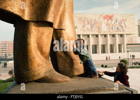 Kleiner Junge ermutigt von seiner Mutter, küssen die Füßen der Statue von Enver Hoxha, der Gründer des kommunistischen Staates, Tirana, 1990 Stockfoto