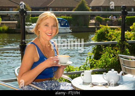 Frau trinkt Kaffee im Freien an einem Fluss Stockfoto