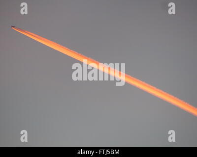 Flugzeug mit Jet Auspuff beleuchteten Orange durch die untergehende Sonne Stockfoto