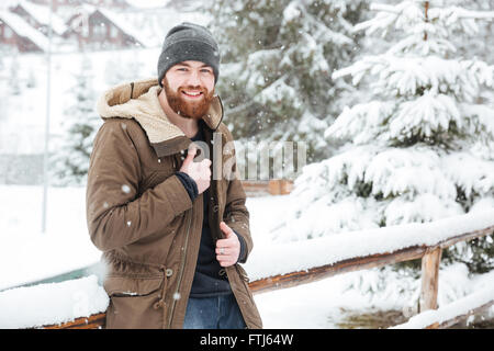 Happy bärtiger jungen Mann stehen und Lächeln auf den Lippen im Winter im freien Stockfoto