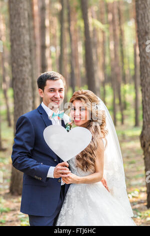 glückliche Bräutigam und die Braut in einem Park mit Zeichen als Herz Stockfoto