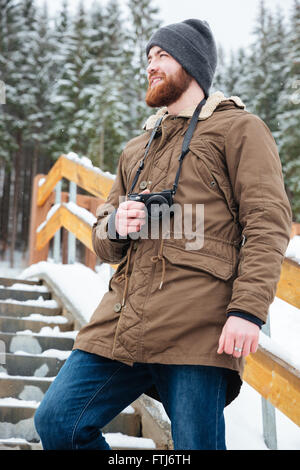 Lächelnd attraktive bärtigen Mann Fotografieren auf Treppe im Winterwald Stockfoto