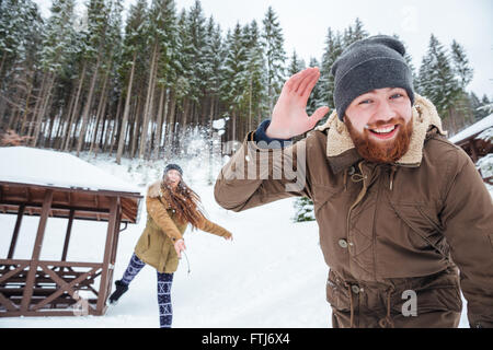 Glückliches junges Paar spielen Schneebälle im Winterwald Stockfoto