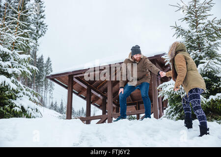 Glücklich attraktive junge Mann hilft seiner Freundin auf Spaziergang Berge im winter Stockfoto