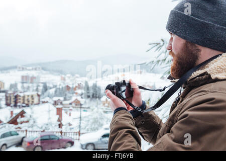 Bärtigen jungen Mann Fotografieren der Ansicht im Freien im Winter konzentriert Stockfoto