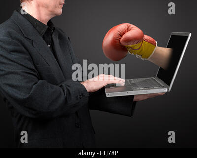 Mann im schwarzen Hemd und Anzug hält einen Laptop und Win Boxhandschuh Punsch Stockfoto
