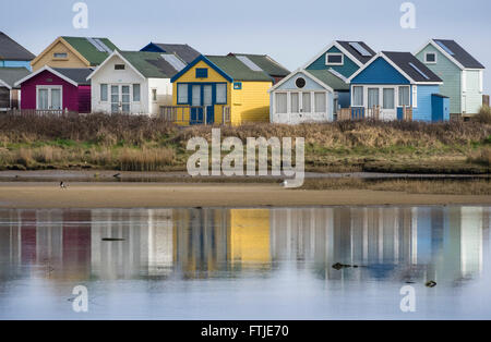 Eine Reihe von Strandhütten und ihre Überlegungen in einer Lagune von Christchurch Harbour Hengistbury Head, Bournemouth, Dorset, England, Großbritannien Stockfoto