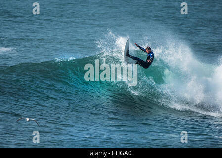 Ein Surfer in einer spektakulären Aktion wie er reitet eine Welle in Camborne, Cornwall, England. Stockfoto