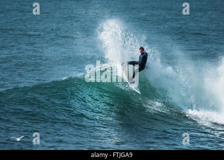 Ein Surfer in einer spektakulären Aktion wie er reitet eine Welle in Camborne, Cornwall, England. Stockfoto