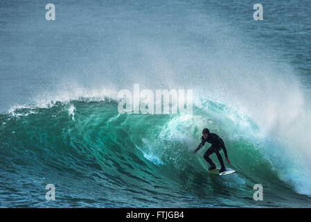 Ein Surfer in einer spektakulären Aktion wie er reitet eine Welle in Camborne, Cornwall, England. Stockfoto