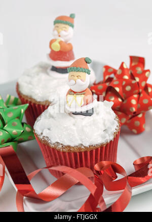 Weihnachten-Cupcakes mit traditionellen Dekorationen und Schlagsahne Stockfoto