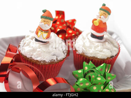 Weihnachten-Cupcakes mit traditionellen Dekorationen und Schlagsahne Stockfoto