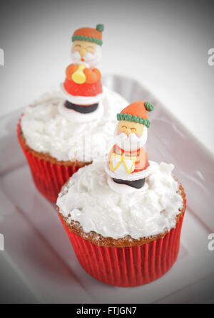 Weihnachten-Cupcakes mit traditionellen Dekorationen und Schlagsahne Stockfoto