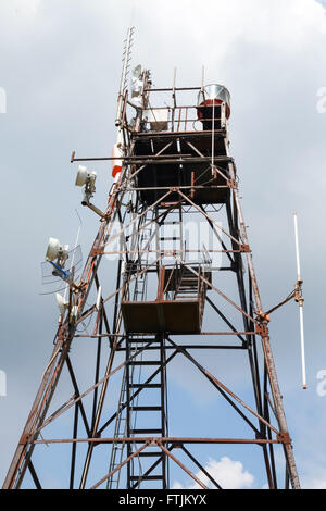 Telekommunikation-Funkturm mit verschiedenen Sendern und Empfängern Geräten über bewölktem Himmel Stockfoto