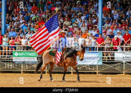 Frau Reiten und paradieren die Nationalflagge der USA rund um die Arena vor einem Rodeo, Arcadia, Florida, USA Stockfoto