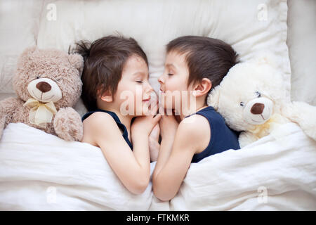 Zwei jungen mit Teddy Bären, im Bett liegend, schlafen am Nachmittag umarmt Spielzeug Stockfoto