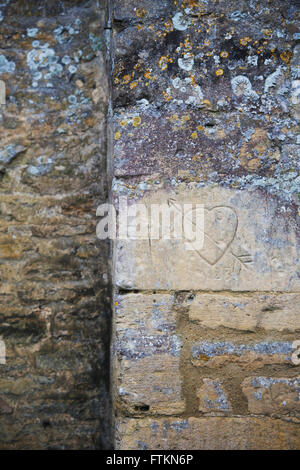 Geschnitzte Herz auf einer Steinmauer Cotswold. Bibury, Gloucestershire, England Stockfoto