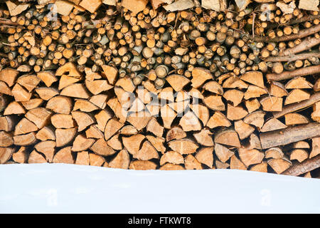 Brennholz gestapelt im Winter. Holz-Haufen mit Schnee für Brennholz gestapelt Stockfoto