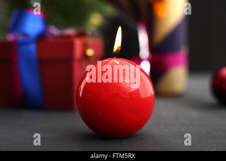 Weihnachtsgeschenk Idee wie ein Geschenk zu schmücken. Schön verpacktes Geschenk. Rote Kerze, festliche Atmosphäre im Haus. Stockfoto