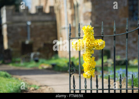 Ostern-Narzisse Kreuz vor den Toren der Kirche St. Peter & St Paul. Könige Sutton, Banbury, Northamptonshire, England Stockfoto