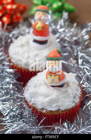 Weihnachten-Cupcakes mit traditionellen Dekorationen und Schlagsahne Stockfoto