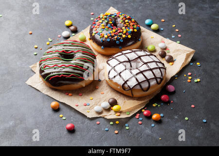 Bunte Donuts und Süßigkeiten auf Steintisch Stockfoto