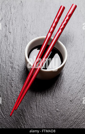 Japanische Sushi-Stäbchen über Sojasauce Schüssel auf schwarzem Stein Stockfoto