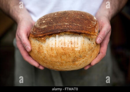 Ein Bäcker hält ein Brot frisch gebackenes Soda in seinen Händen. Stockfoto