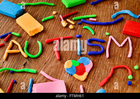 das Wort Autismus aus Knetmasse in verschiedenen Farben auf einer rustikalen Holzoberfläche gefertigt Stockfoto