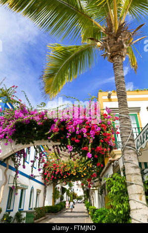Malerischen Fußgängerzone mit Bougainvillea und touristischen paar Wandern, Puerto de Mogan Gran Canaria Kanaren Spanien Stockfoto