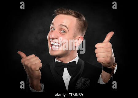 Geschäftsmann mit Daumen oben auf dunklem Hintergrund. Stockfoto