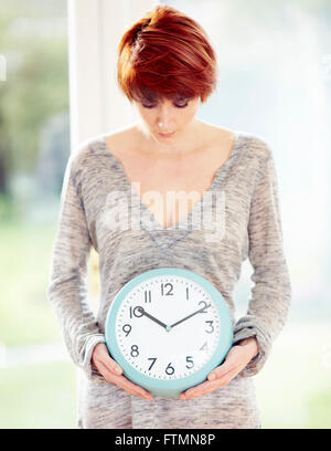 Frau stand hielt eine Uhr Stockfoto