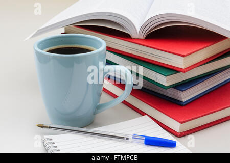 Schülers studieren Szene mit Stapel Bücher und Tassen starken schwarzen Kaffee durch ein Notizbuch und Stift auf einem Schreibtisch für die Überarbeitung für Prüfungen. England-UK-Großbritannien Stockfoto