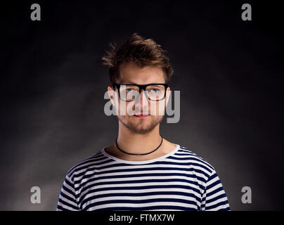 Mann im gestreiften T-shirt und Brillen vor schwarzem Hintergrund. Stockfoto