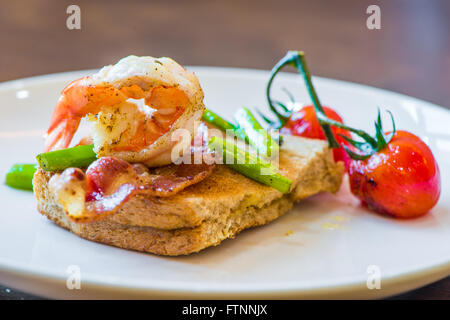 Sandwich mit pochiertem Ei, Parmaschinken und Tomaten Stockfoto