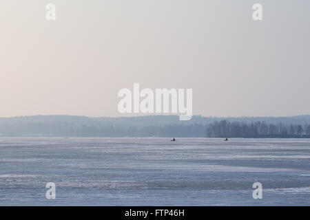 Weiten Blick auf einem zugefrorenen See in Finnland am Morgen. Zwei Eis Fisher in der fernen Zukunft. Kopieren Sie Raum. Stockfoto