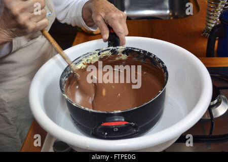 Frau Schmelzen der Schokolade in einem Wasserbad für die Produktion von handgefertigten Easter eggs Stockfoto