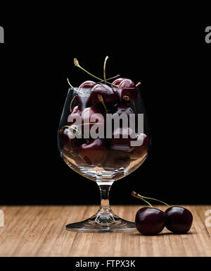 Schnaps Glas voll mit frischen Kirschen Stockfoto